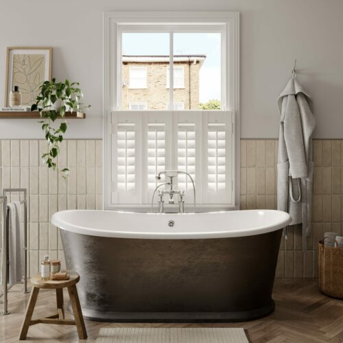 Neutrally decorated bathroom with a copper roll top bath and a sash window fitted with a cafe style shutter
