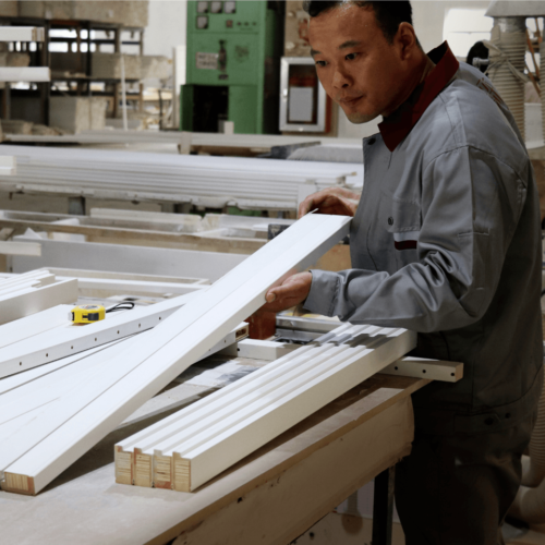 Person working with timber shutter components in a factory